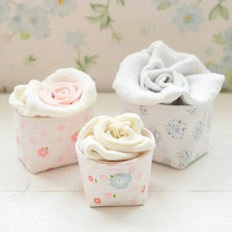 Three decorative fabric flowers in patterned containers.